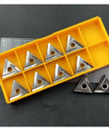 Ten silver TNMG carbide turning inserts with mounting holes in a yellow plastic organizer.