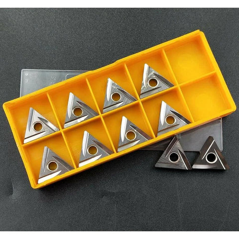 Ten silver TNMG carbide turning inserts with mounting holes in a yellow plastic organizer.