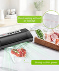Powerful Vacuum Sealer For Food With Automatic Mode sealing steak and vegetables, black silver compact design on kitchen counter.