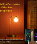 Industrial Glass Globe Desk Lamps Set Of 2 With USB Charging Ports Gold Metal Bedside Table Lamps Stepless Dimmable Brightness Perfect For Living Room Or Bedroom LED Bulbs Included, shown on bedside with phones charging.