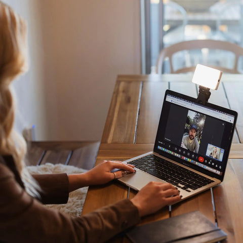 Person using video conference lighting kit for Zoom and live streaming, mounted on a laptop, enhancing screen presence.