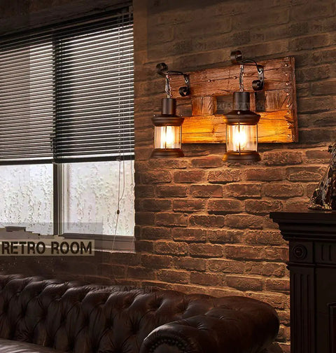Industrial Farmhouse Wall Sconce Lighting Fixture With Wooden Base And Two Lantern Lights in cozy living room setting