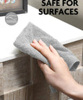 Close-up of gray Fantasticlean microfiber cleaning cloth in hand while wiping a white kitchen counter.
