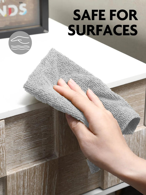 Close-up of gray Fantasticlean microfiber cleaning cloth in hand while wiping a white kitchen counter.