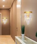 Gold Crystal Wall Sconce Lighting Fixture With Four Tier K9 Crystals in hallway, warm glow illuminating wall and plants