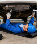Mechanic using Rolling Creeper Mat For Mechanics 58x27 Inch Durable Oil And Water Resistant Garage Floor Pad foldable car repair pad.