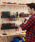 Man using 2 Pack Screwdriver Organizer Wall Mount Set With 28 Tool Capacity 14 Top And Bottom Holes Per Holder Metal Pliers Organizer Fifteen Point Eight Inch Long Space Saving Storage For Garage Workshop And Home Workbench mounted on wall.