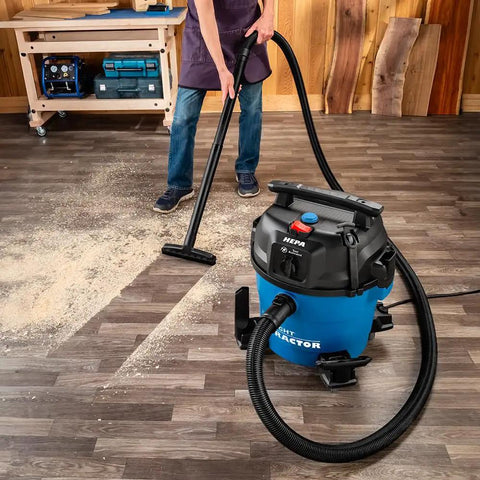 Person using 9 Gallon HEPA Dust Collector Auto Starts With Your Power Tools on wooden floor with debris