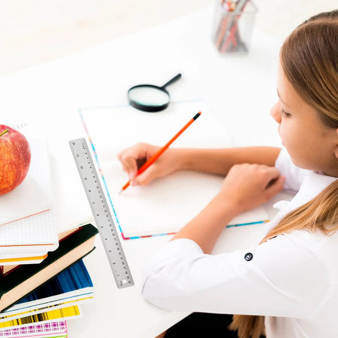 Workhorse Stainless Steel Ruler With Non Slip Cork Back Dual Inches And Centimeters Scale next to student writing on desk