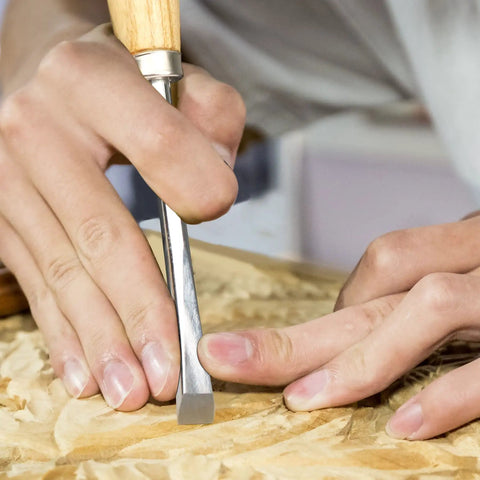 Close-up of a hand using a Six Piece Wood Carving Tools And Kickass CRV Steel Chisel Set With Rust Resistant Coating And Fishtail V Gouge Design For Fine Woodworking Where Clean Cuts Truly Deliver The Goods On Every Detailing Project Today.