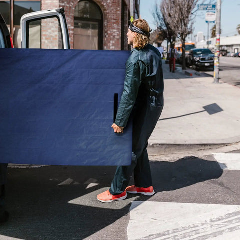 Person carrying a waterproof mattress bag for moving and storage, queen size 82 inch by 63 inch by 15 inch, with strong handles