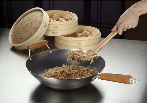 Go-To 14-Inch Carbon Steel Wok With Bamboo Handle for stir frying on stovetop, noodles being stirred