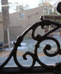 Kick Up Your Space With These Heavy Duty Victorian Corner Shelf Brackets Solid Cast Iron Rustic Brown Finish Built Tough For Windows Vintage Look Set Of Four close-up of cast iron bracket against window.