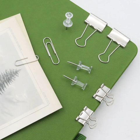 Complete Office Supplies Set With Paper Clips, Binder Clips, And Push Pins in a handy box on a green notebook for office use.