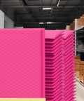 Stack of Hot Pink 8.5 X 12 Inch Bubble Mailers Dope Self Seal Padded Envelopes in a storage area