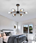 Lit Six Light Black Glass Globe Chandelier in bedroom, modern ceiling pendant lighting fixture with smoke gray glass globes.