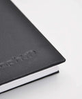 Close-up of The Book A4 Spiral Notebook with 80 pages of extra white 300g marker paper, black hard cover, corner view.