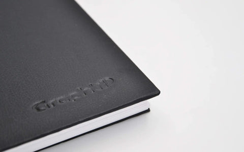 Close-up of The Book A4 Spiral Notebook with 80 pages of extra white 300g marker paper, black hard cover, corner view.
