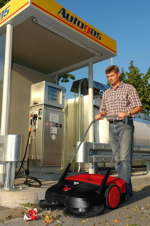Heavy Duty Turbo Hand Sweeper With Dual Disc Brushes And Beltless Drive works at gas station, cleaning fine dust and debris.