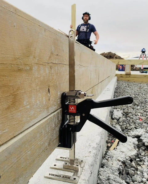 Viking Arm handheld jack/clamp installed on wooden beam at construction site.