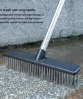 Heavy Duty Push Broom Brush With Tough Stainless Steel Bristles And Solid Handle For Patio Driveway Concrete Deck And Tile Floors Hard As Nails Cleaner close-up shot of wire brush with long handle on concrete surface