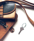 Open brown leather purse with a key attached to a One Inch Diameter Giveaway Key Ring Pack Of 1000 In Silver Finish Zinc Plated Steel Spring Wire