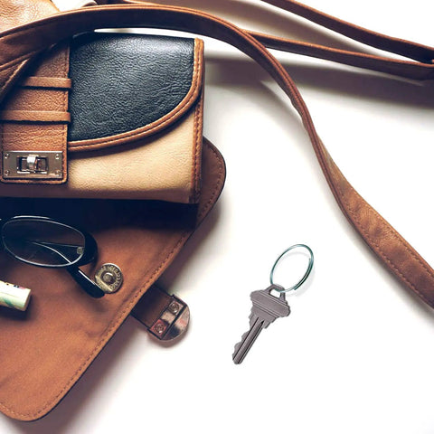 Open brown leather purse with a key attached to a One Inch Diameter Giveaway Key Ring Pack Of 1000 In Silver Finish Zinc Plated Steel Spring Wire