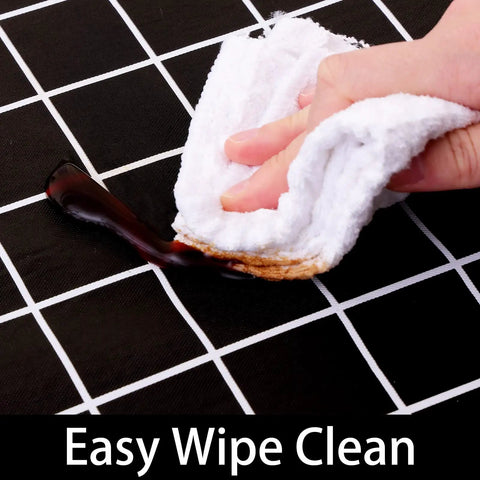 Close-up of Waterproof Elastic Fitted Vinyl Table Cover 30x72 With Flannel Backing, being wiped clean, demonstrating stain resistance.