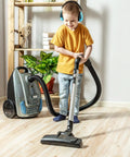 Child vacuuming wearing Four Pack Kids Ear Protection Earmuffs Adjustable Noise Reduction 27NRR Noise Cancelling Earmuffs, yellow shirt.