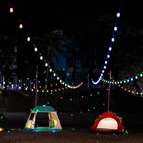 Smart RGB Outdoor String Lights 96ft With Independent Bulb Color Control lighting up a night scene over tents.