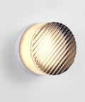 Modern Round LED Wall Sconce, 8W Smoke Grey Striped Glass Vanity Light with warm white LED, round design, mounted on wall.