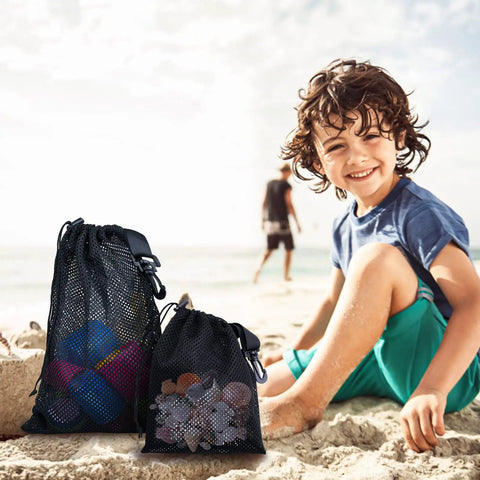 Beach scene with a child and two 10 Pack Mesh Drawstring Bags With Clips Grab And Go Portable Nylon Storage Pouches.