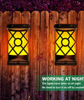 Solar Flame Lanterns Outdoor Lights 6 Pack Waterproof Wall Lanterns With Realistic 3D Flickering Flames illuminating a wooden fence.