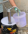 Heavy Duty Manual Oil Drum Pump With Ergonomic Handle For High Pressure Transfer And Effortless Sump Cleaning in use, pouring oil into a bucket.
