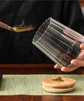 Level Up Your Kitchen With This Tough Clear Glass Storage Jar Boasting A Tight Airtight Wooden Lid Sealed Cap For Grains Coffee Beans Candy And Spices To Keep Everything Fresh On Hand with dried tea leaves.