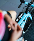 Cyclist on bike using KICKR Mat All Purpose Floor Mat For Indoor Cycling Trainers And Home Workouts Water Resistant No Slip Texture