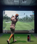 Golfer practicing indoors with simulator, Square Golf Launch Monitor Protective Shield Case in clear acrylic on floor.