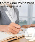 Person using a Gel Pens Set 12 Pack 0.5mm Quick Dry Black Ink Fine Point For Journaling And Note Taking at a desk