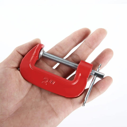 Hand holding a single red clamp from the 16 Pack 2 Inch C Clamps Set Beefy Heavy Duty Quick Grip Clamps With Throat Depth 1 3 16 Inch.