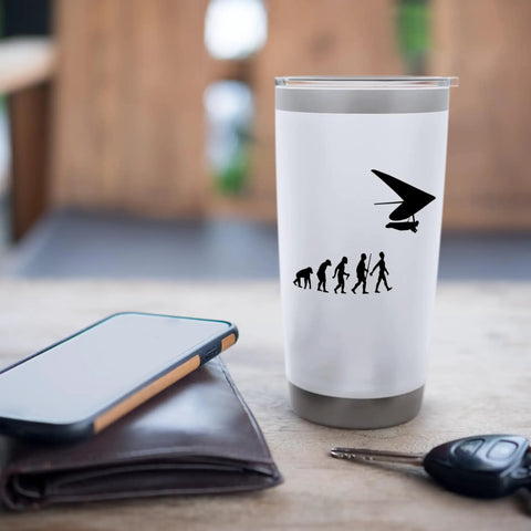 White hang glider themed stainless steel insulated tumbler with evolution graphic, 20 oz, on a table with phone and keys.