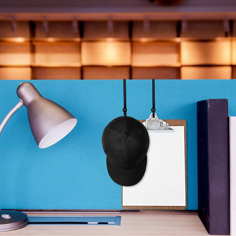 Four Pack Cubicle Coat Hooks For 2 Inch Wide Panels, Double Arm Metal Hangers holding a black cap and clipboard on cubicle wall