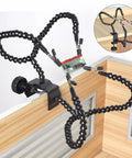 Third Hand Soldering Station with Adjustable Gooseneck Arms holding circuit board, clamped to wooden desk edge.