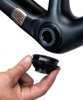 Hand holding 12-Notch Bottom Bracket Tool For Praxis M30, Three Eighths Inch Drive Ratchet Compatible, close to a bike frame.