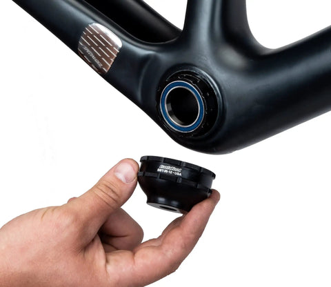 Hand holding 12-Notch Bottom Bracket Tool For Praxis M30, Three Eighths Inch Drive Ratchet Compatible, close to a bike frame.