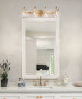 Gold Modern Bathroom Vanity Lights Over Mirror With Four Clear Glass Shades above a white vanity