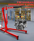 Heavy Duty 2 Ton 4400 Lbs Engine Hoist Folding Alloy Steel Cherry Picker Portable Hydraulic Crane in workshop lifting an engine.