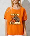 Person wearing orange shirt with 'Team Punch' ape and kitten graphic