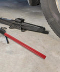 Heavy Duty Red Floor Jack Handle Extension And Jacking Pole Lever With Slick Coating For Quick Setup And Easy Pumps lies beside a black jack.