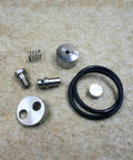 Close-up of waterjet check valve repair kit parts: stainless steel fittings, spring, aluminum cap, and O-ring.