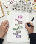 Hands using Vintage Date Clear Stamps Top Shelf Seal Set to create calendar layouts on paper for journal and scrapbooking.